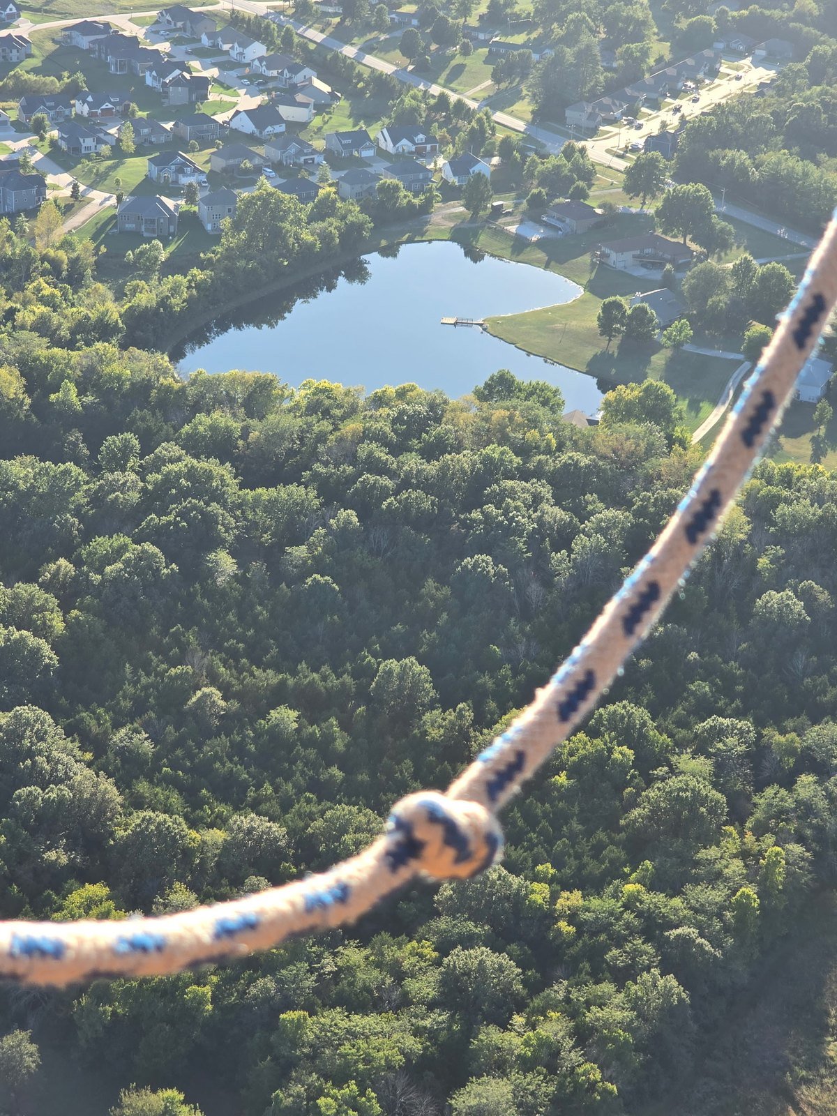 Neighborhood pond and treetops seen from a hot air balloon basket