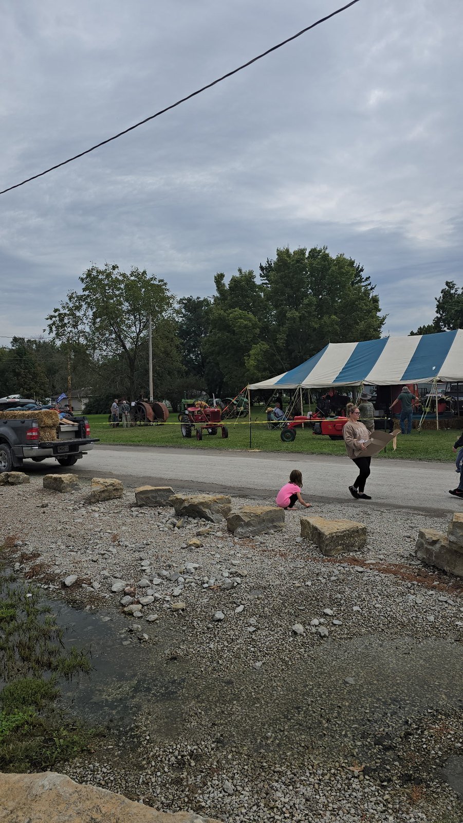 Antique tractors on display under a striped tent at Jamesport Heritage Days