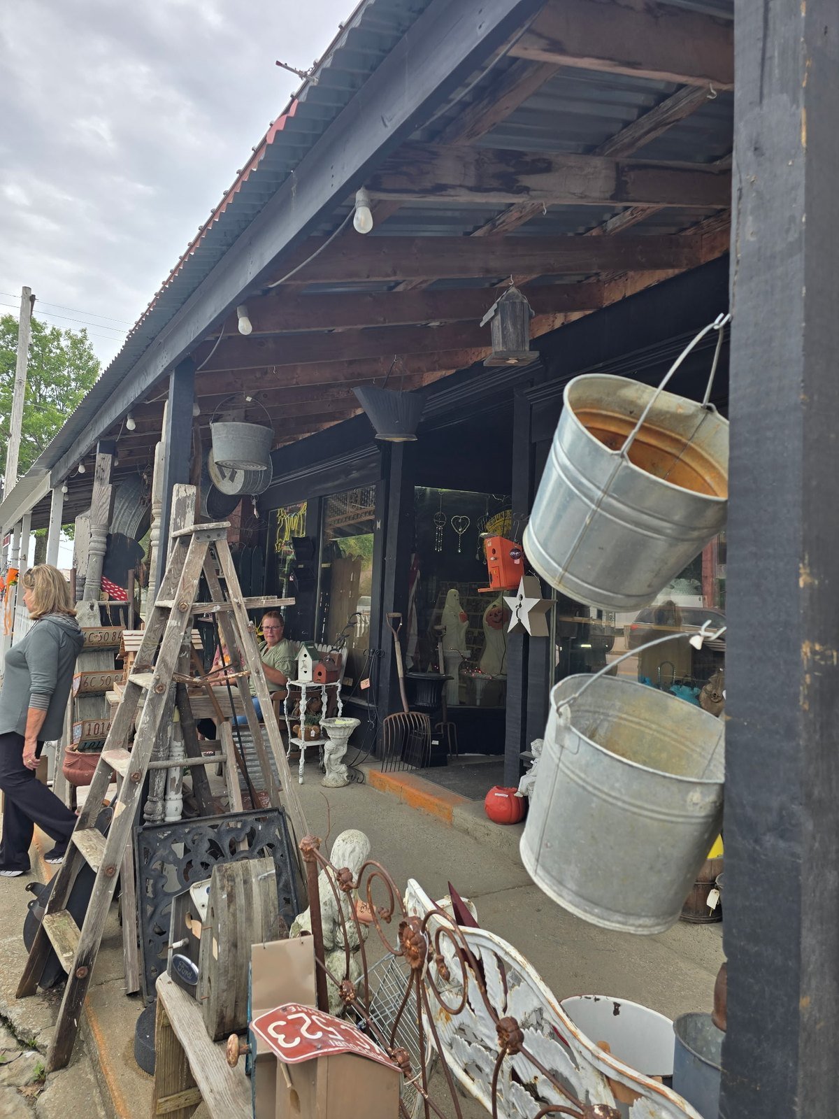 Galvanized buckets, wooden ladders and vintage finds on an antique shop porch