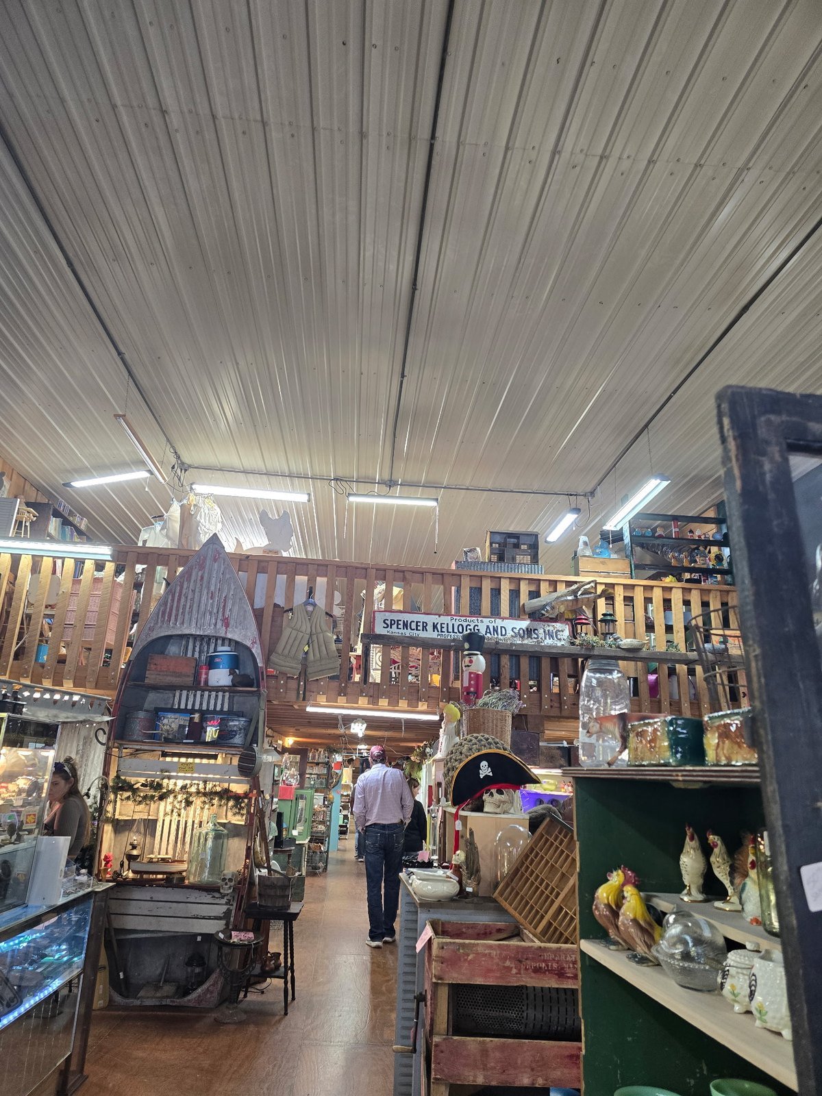 Long aisle inside a Jamesport antique mall with a loft and vintage signs