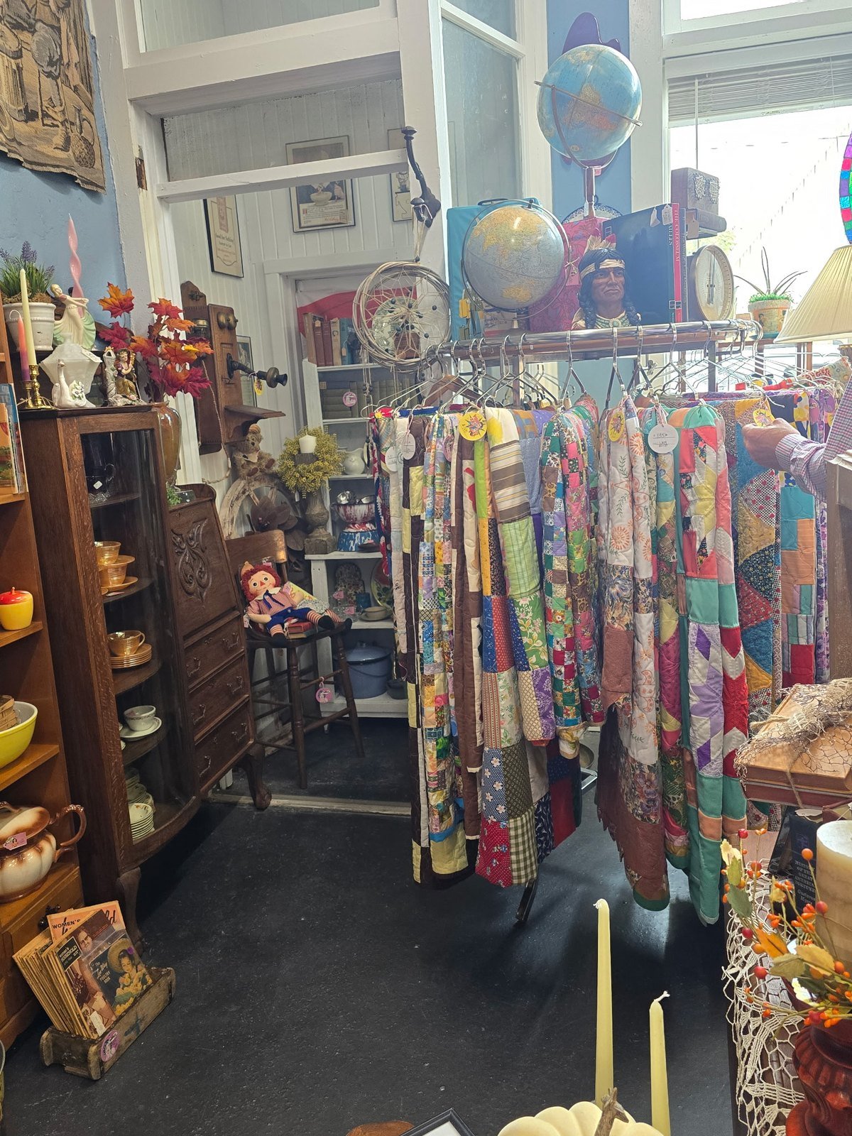 Colorful handmade patchwork quilts hanging on a rack in an antique shop