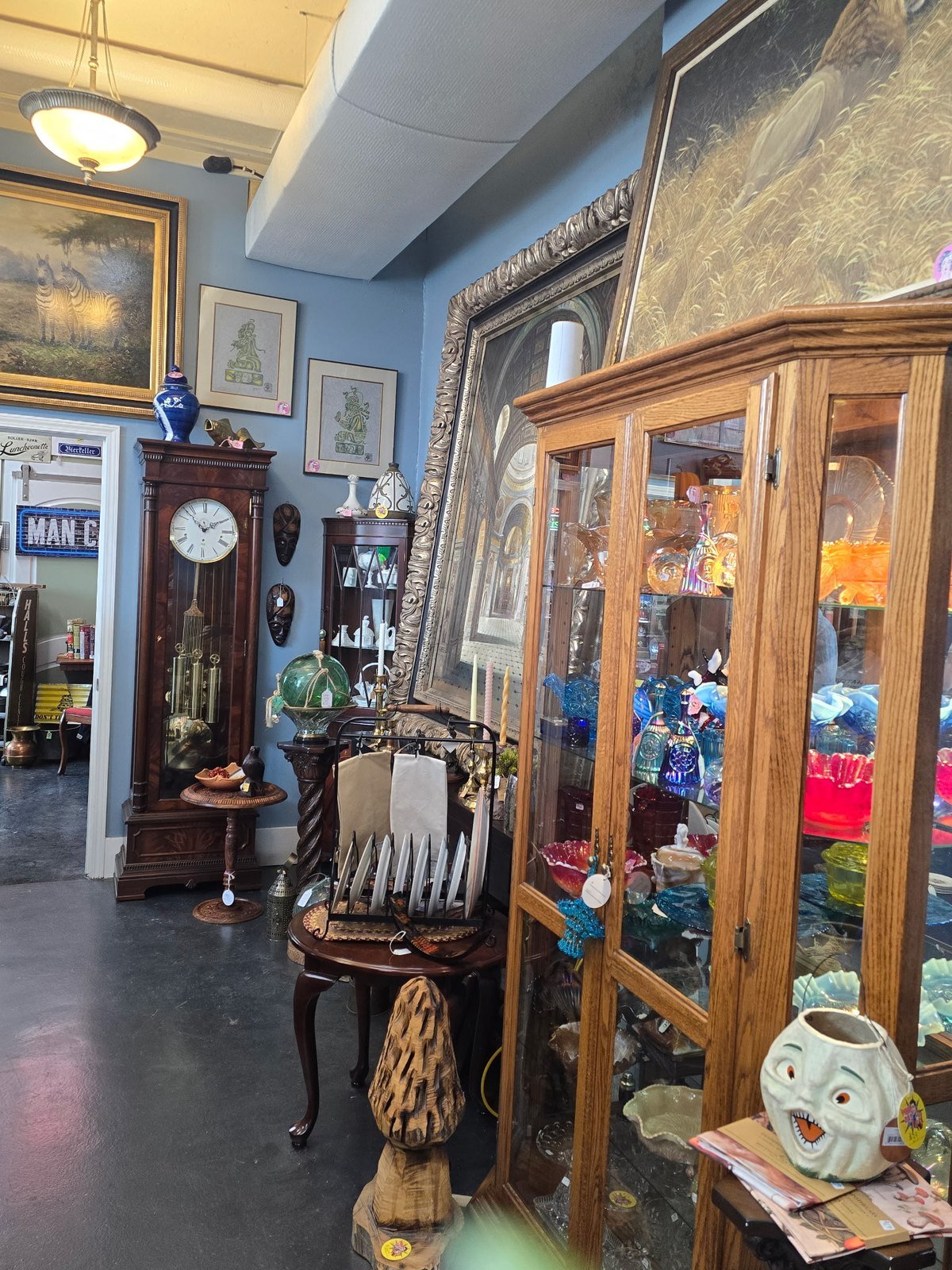 Grandfather clock and cabinet of colored carnival glass in an antique store