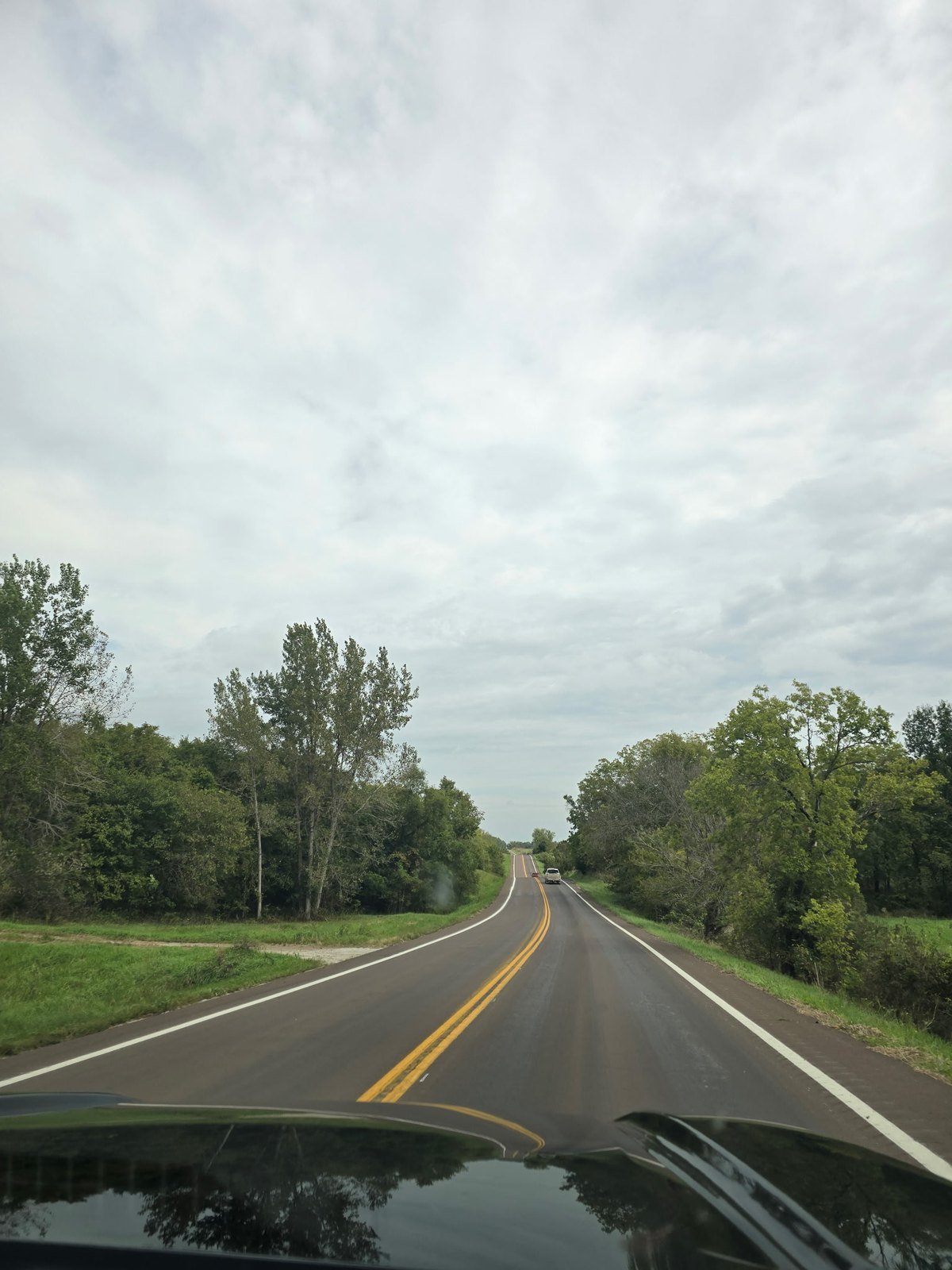 Two-lane country road through green trees on the way to Jamesport, Missouri