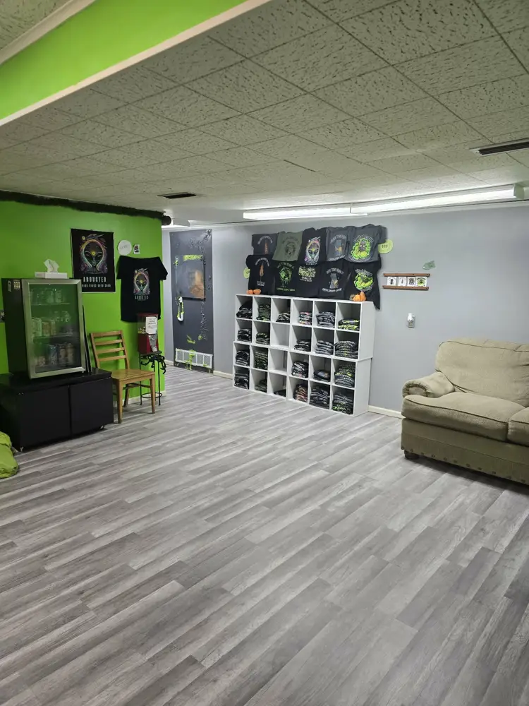 Bright green lobby with couch, drink fridge and T-shirt shelves at Capital Escape