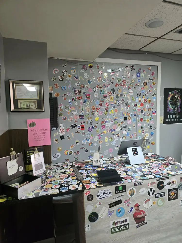 Sticker-covered check-in counter and wall at Capital Escape
